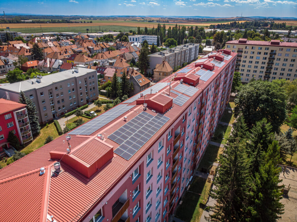 Fotovoltaické panely rozmístěné na střeše bytového domu